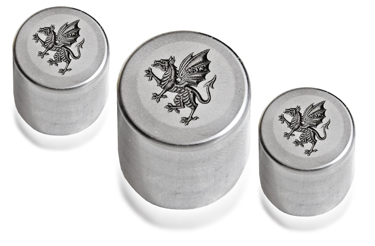 Drei Metallstempel mit graviertem Drachen-Design in verschiedenen Größen.